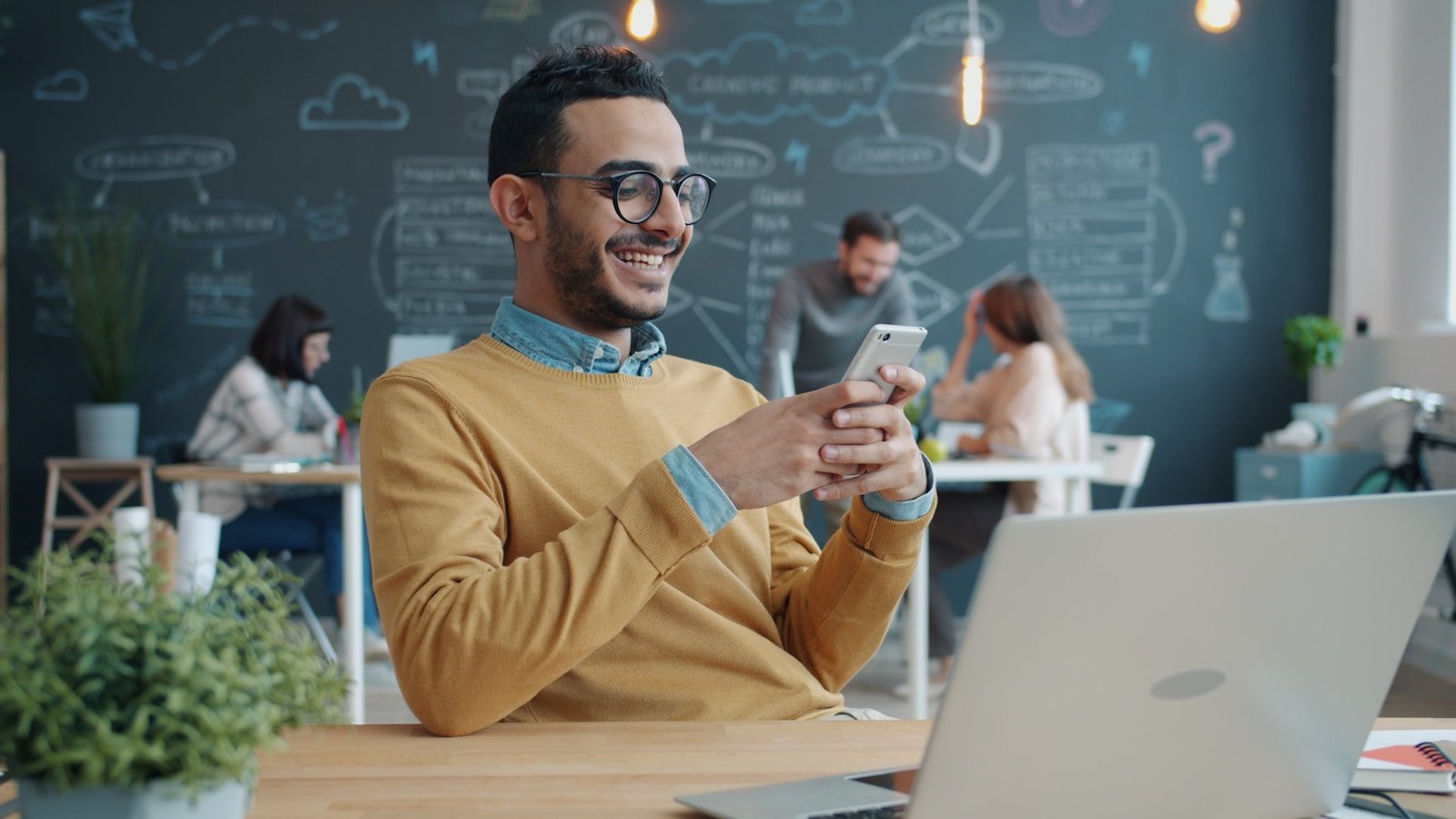 Man smiling while looking at phone in office